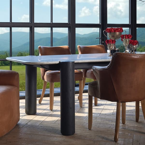 Side view of the marble dining table with black legs and leather chairs
